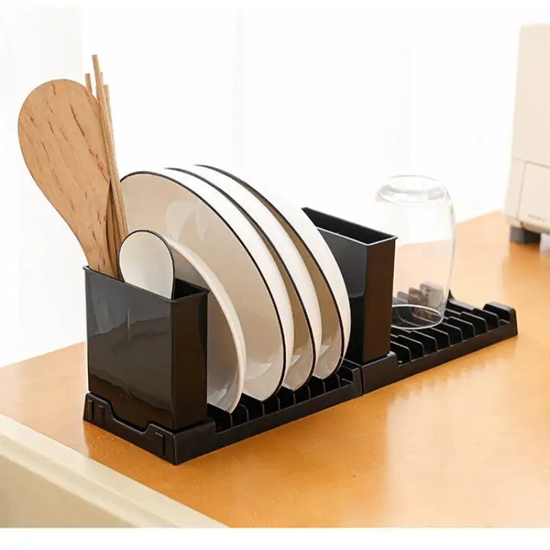 Black plastic dish drying rack on a kitchen counter holding plates and utensils