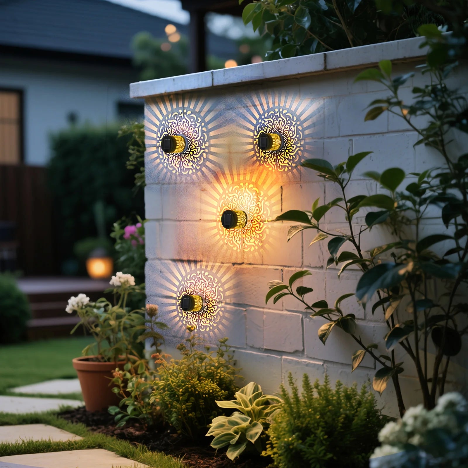 Group of solar wall lanterns on a backyard wall, lighting up plants in the garden