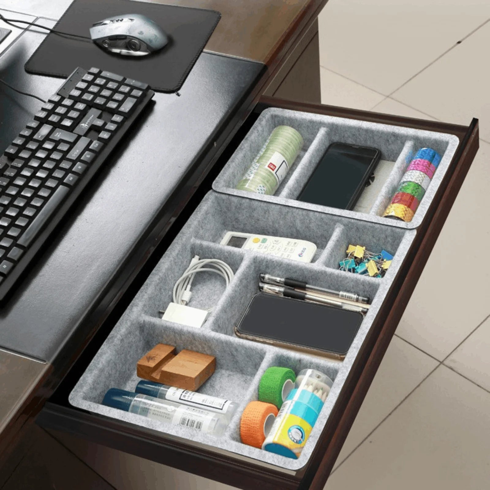 Office drawer with two felt organizer trays neatly storing pens, phone, chargers, and office supplies