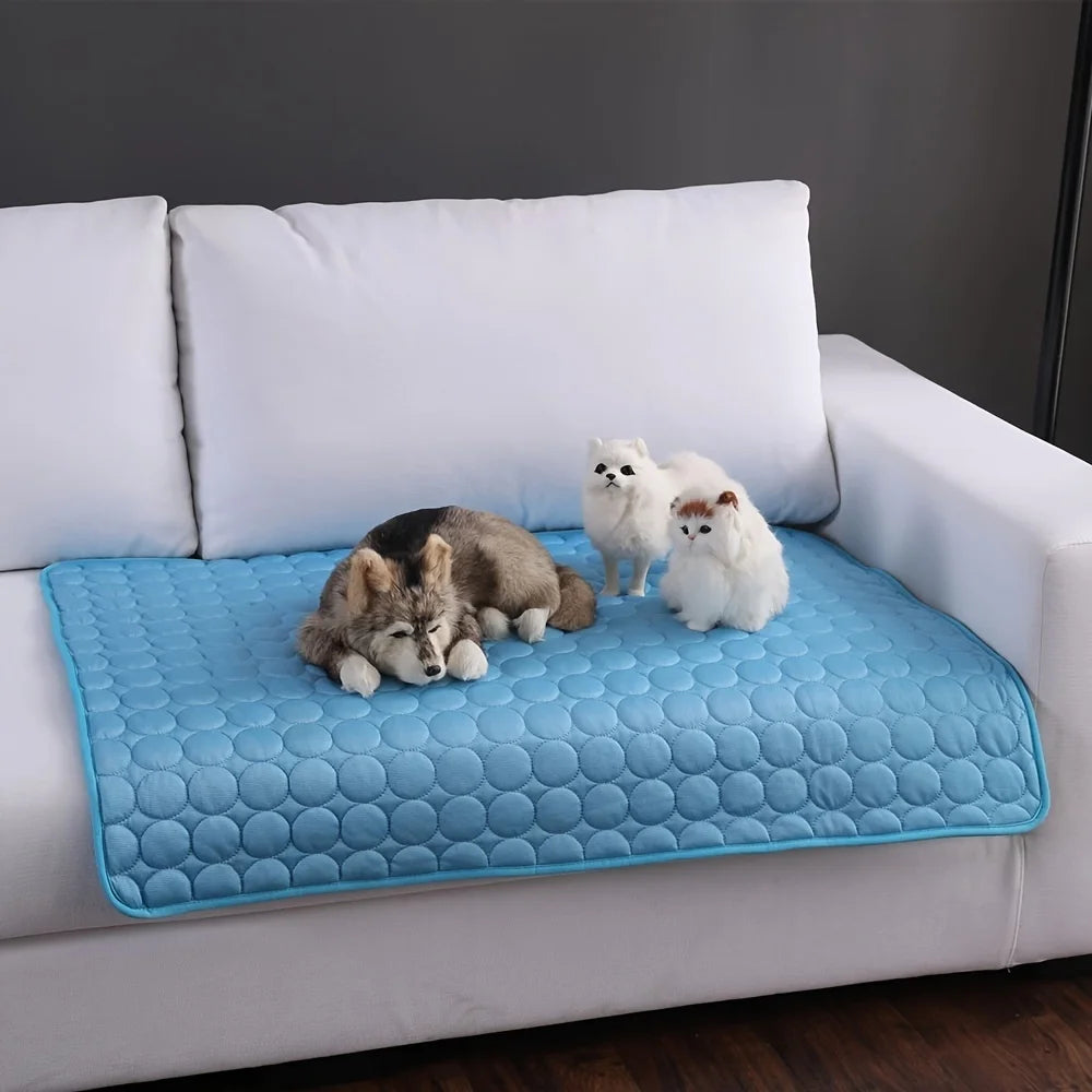 Blue pet cooling mat laid on a white sofa with plush pet toys