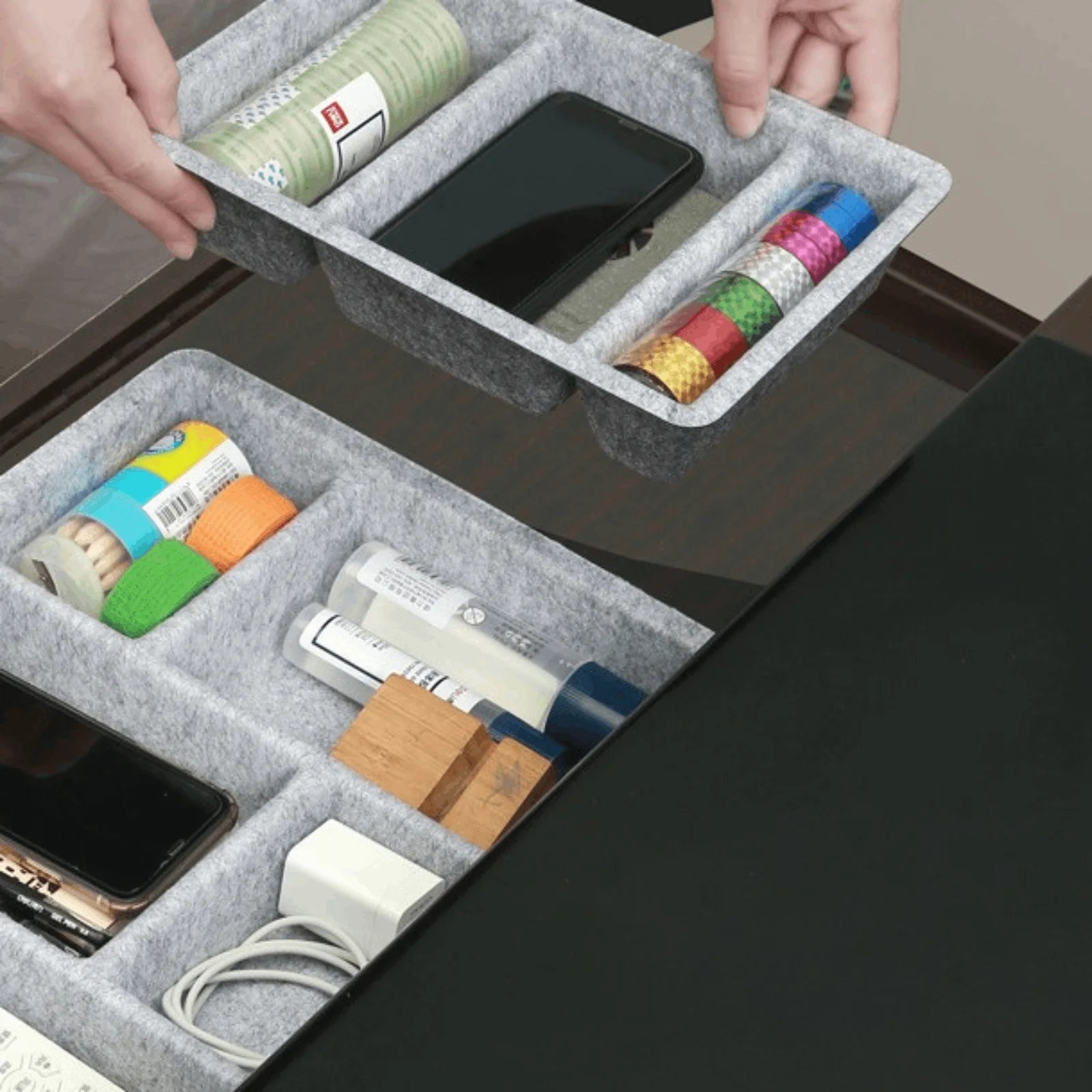 Person placing a felt organizer tray with compartments into a drawer holding stationery and small items