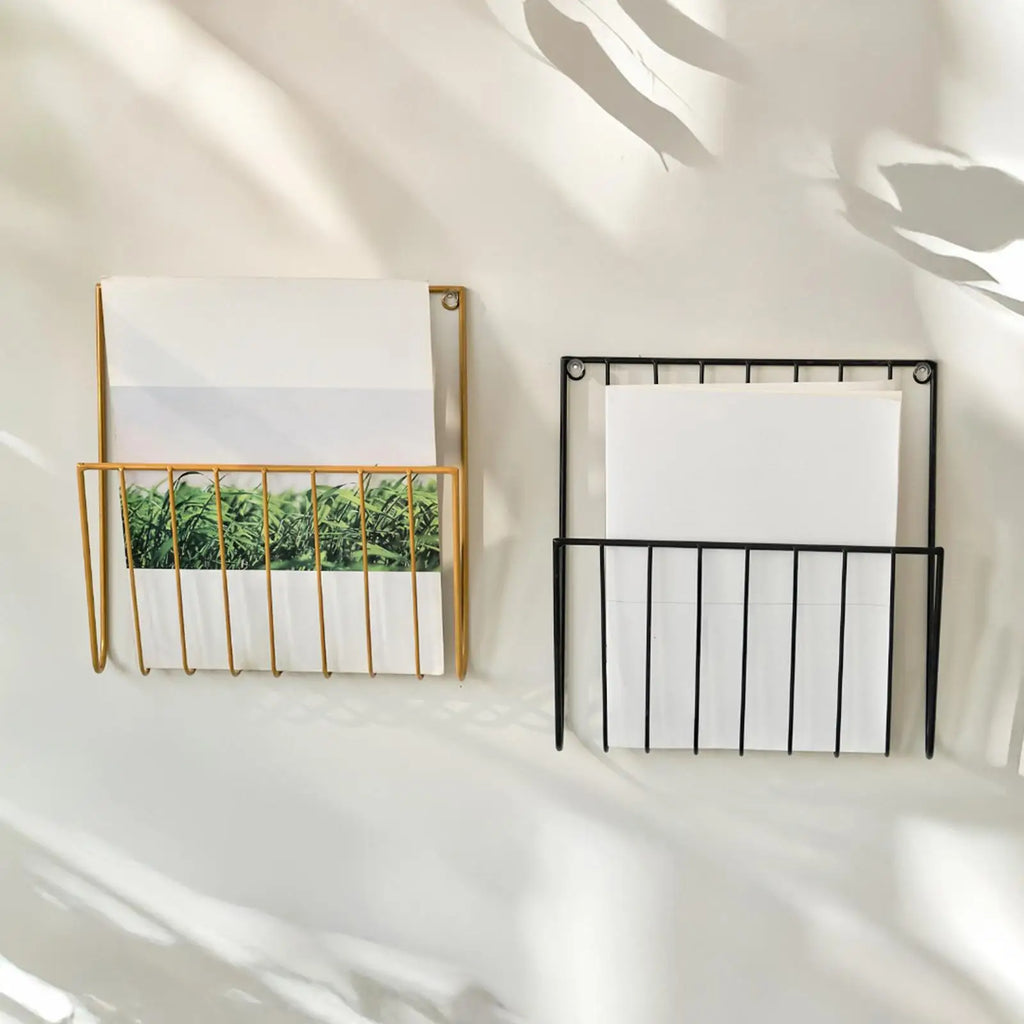 Gold and black iron magazine racks stacked vertically on a wall, each holding papers