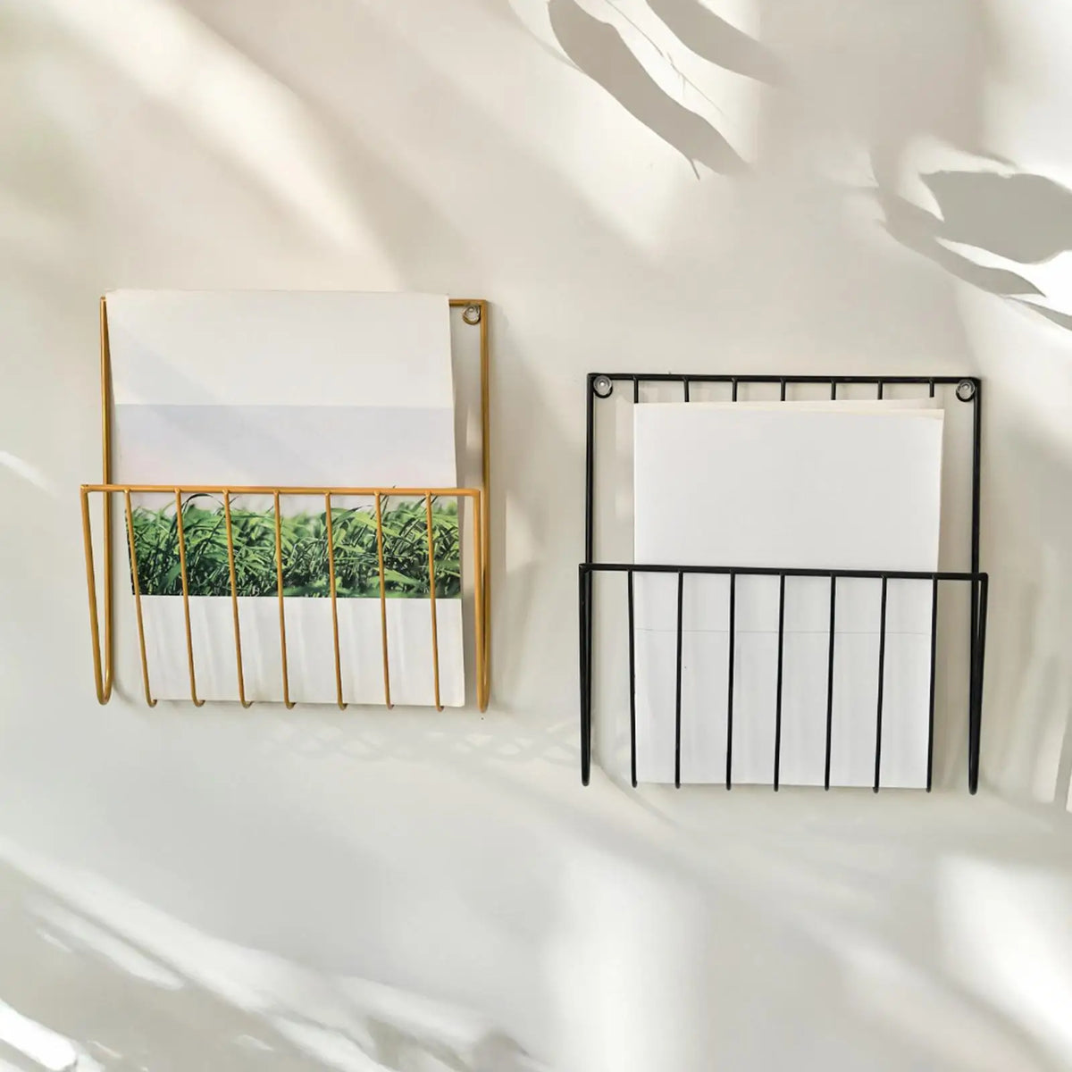 Gold and black iron magazine racks stacked vertically on a wall, each holding papers