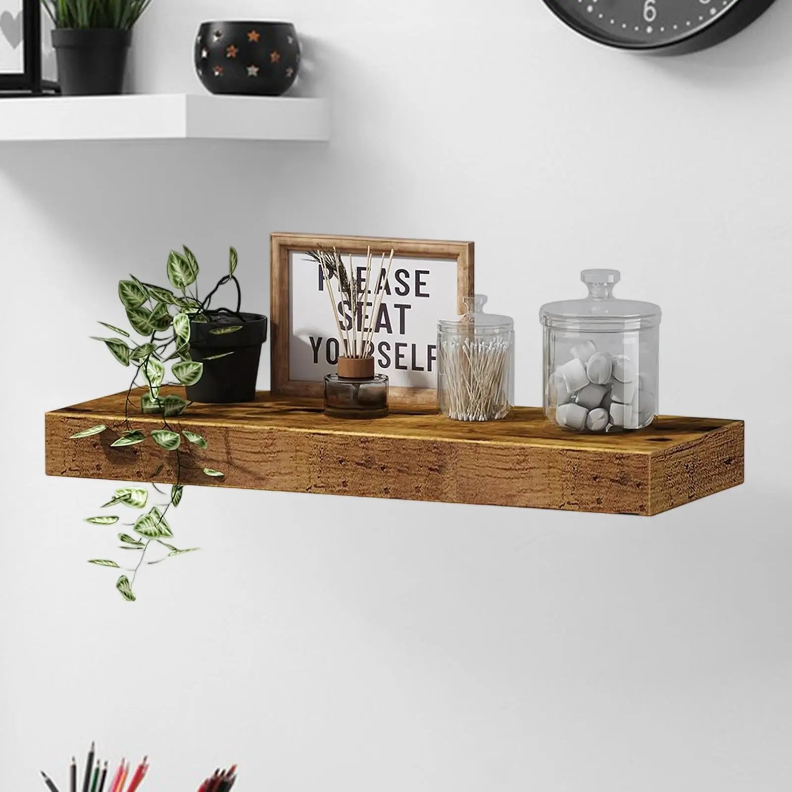 Brown wood floating shelf styled in a living room with decor, jars, and plants