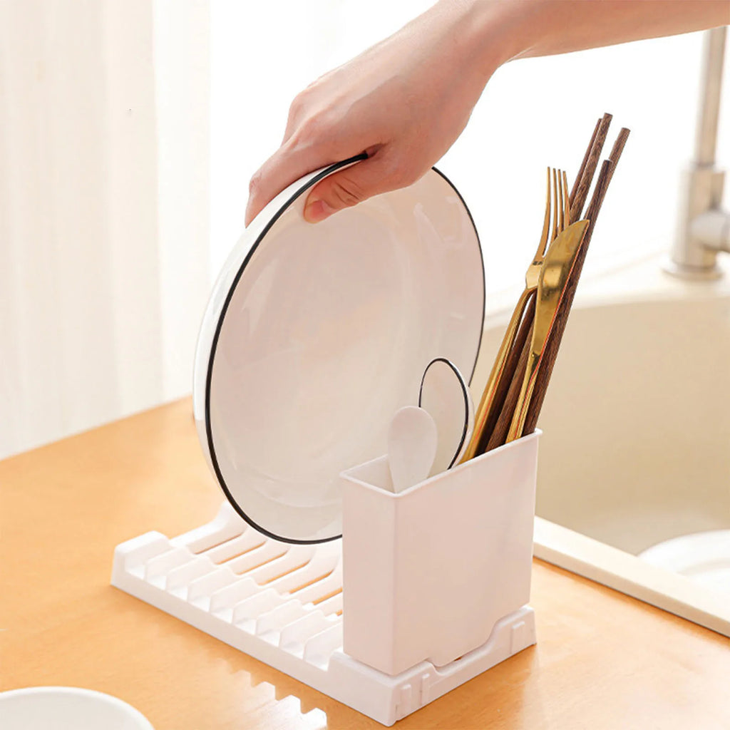 White compact dish rack with plates and gold cutlery placed next to a sink