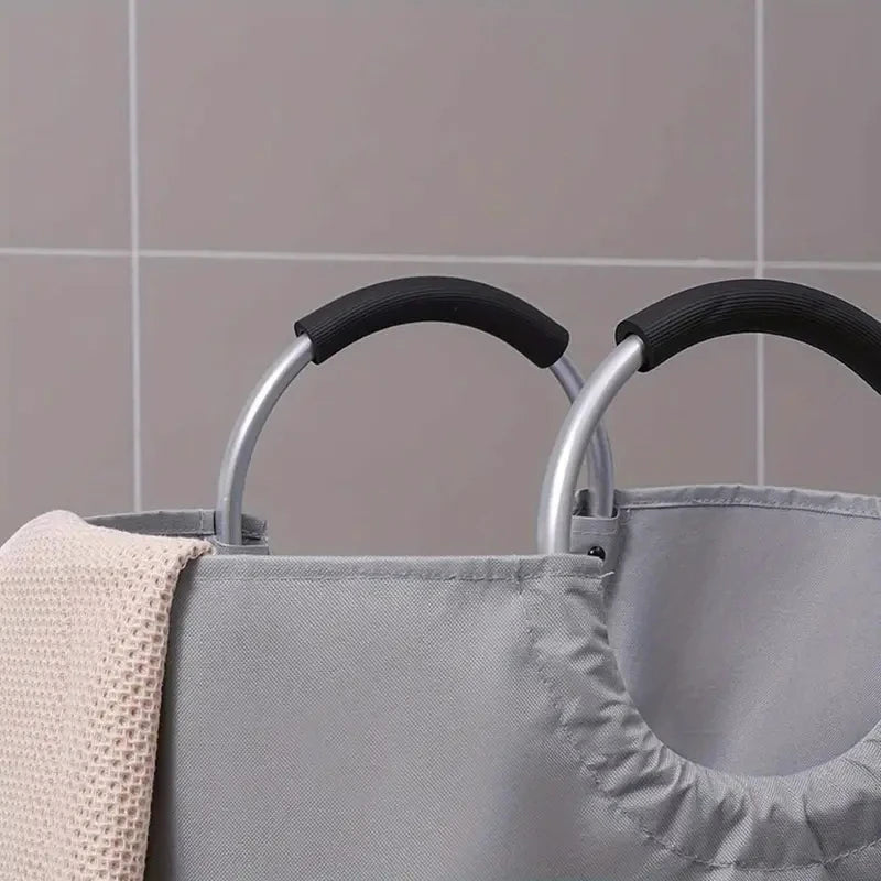 Close-up of soft black handle grips on gray laundry hamper in a tiled bathroom