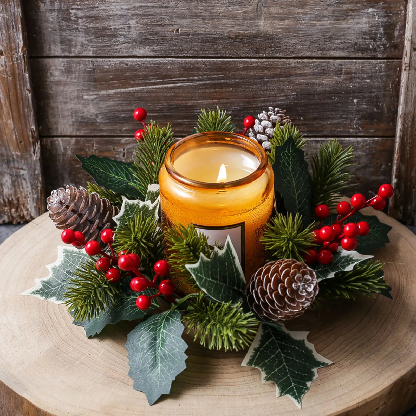 Artificial holiday candle wreath with mixed greenery and red berry accents displayed with an amber candle