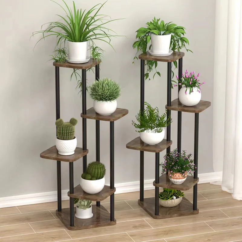 Two multi-level wooden plant stands styled with various indoor potted plants in a living room setting.