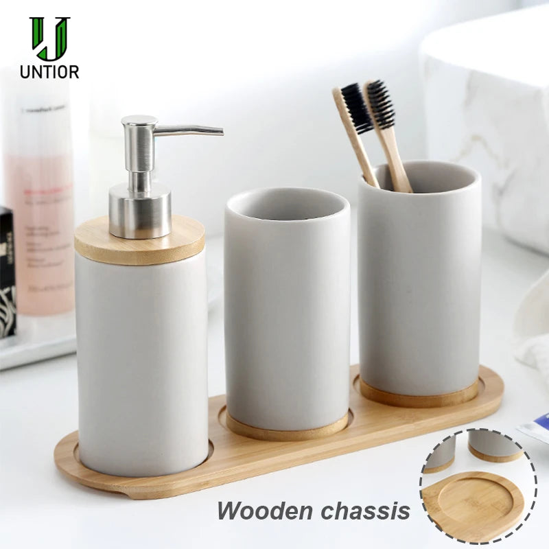 Ceramic bathroom accessory set with bamboo tray in grey: soap dispenser and two tumblers on counter