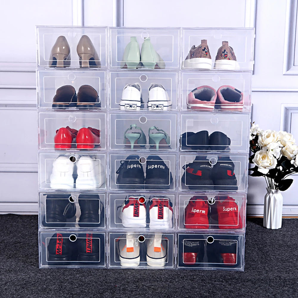 Large collection of clear shoe storage boxes stacked against a wall, each holding a pair of shoes, next to a white flower vase