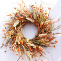 Artificial fall wheat ears wreath with orange and golden foliage hanging on a white front door