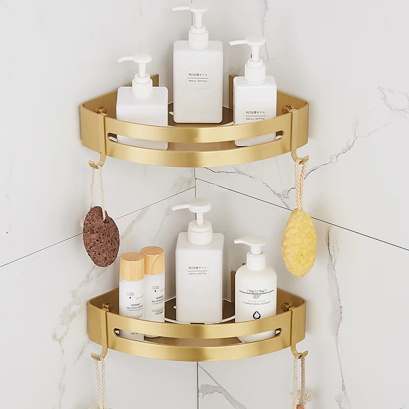 Two brushed gold aluminum corner shelves stacked in a corner with bath bottles and hanging sponges