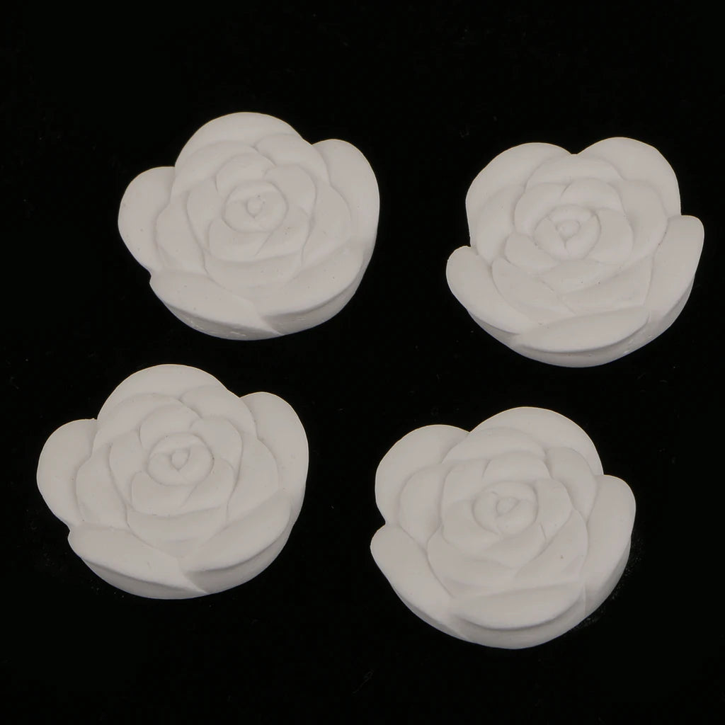 Four white rose-shaped aroma stones for essential oils displayed on black background
