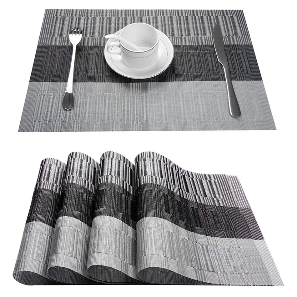 Woven PVC placemat in grey and black with cup, saucer, spoon, fork, and knife set on a table