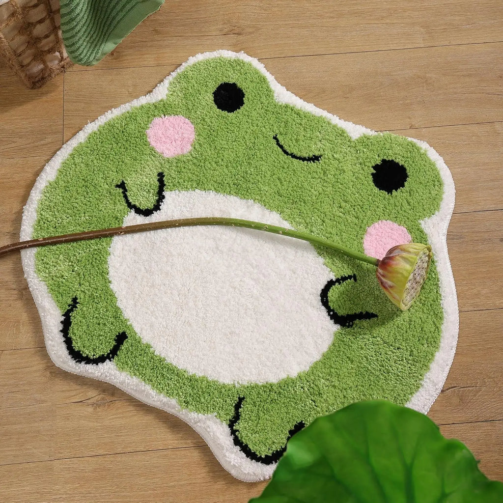 Frog bath rug resting on a wood floor with a flower stem, closeup of round belly and blushing cheeks