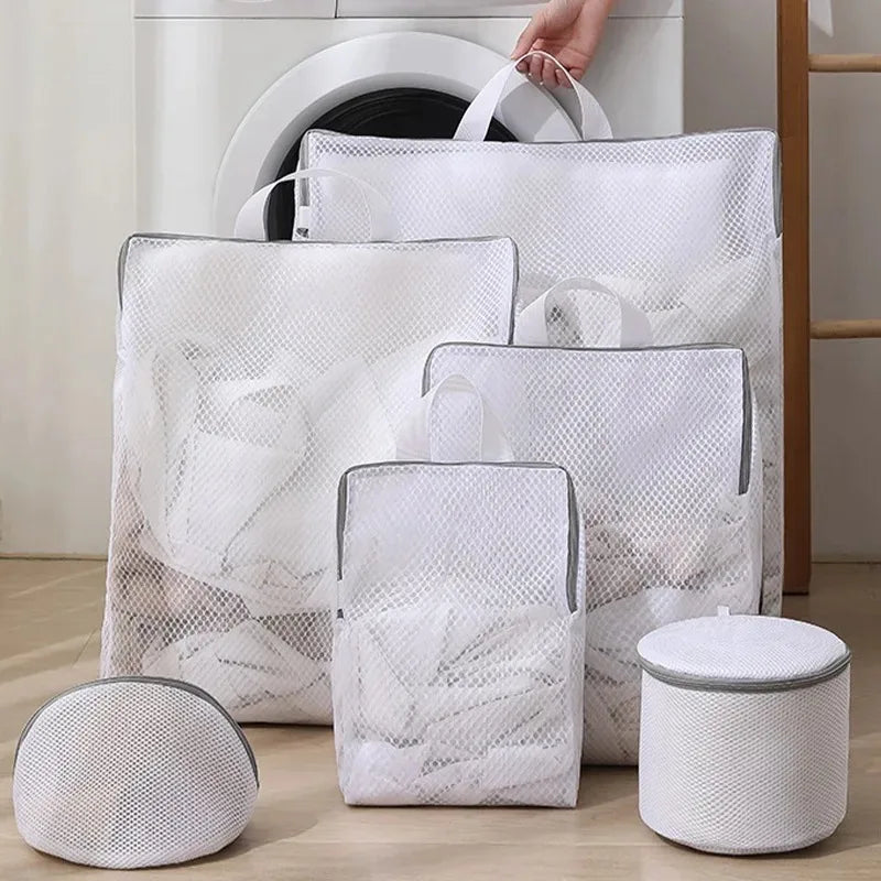 Assorted white mesh laundry bags in rectangular and round shapes, grouped by a washing machine