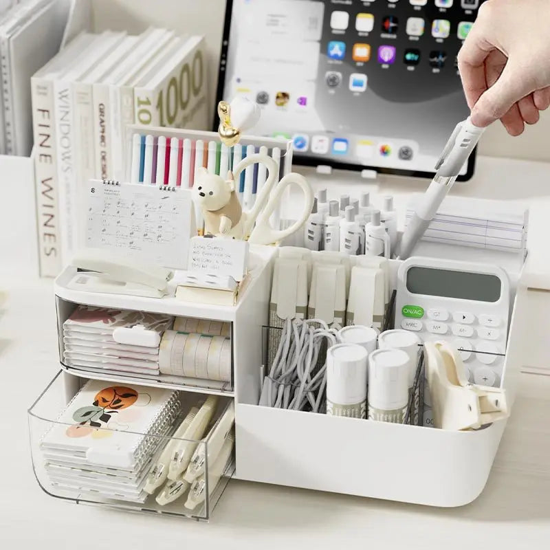 Hand organizing pens into a white desktop drawer organizer with stationery and notes