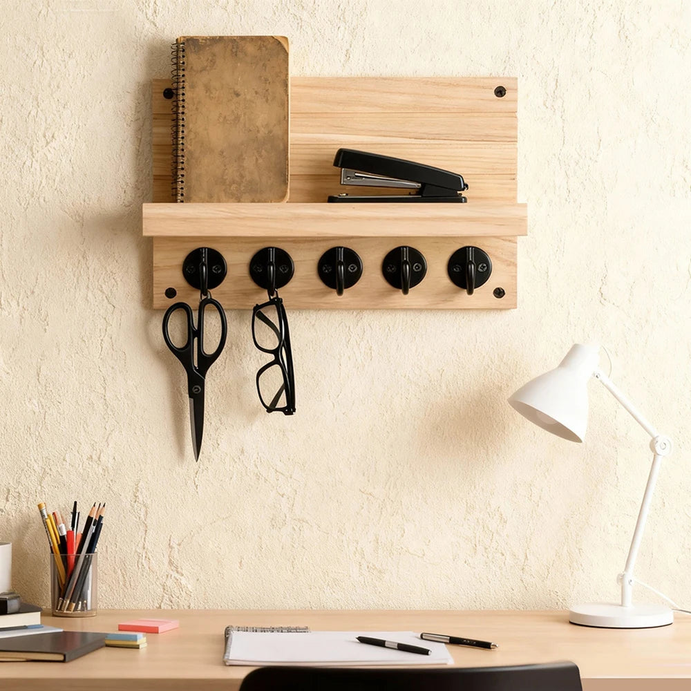 Natural wood wall-mounted key and mail holder with five hooks, shelf holding stationery, with scissors and glasses on hooks.