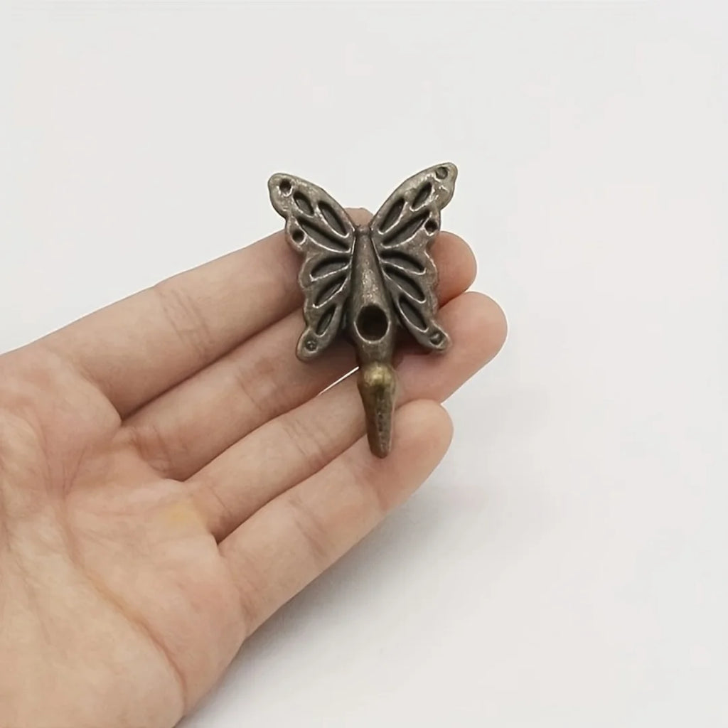 Hand holding one vintage cast iron butterfly wall hook to show scale