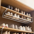 adjustable white under-shelf shoe rack installed in a wardrobe holding shoes