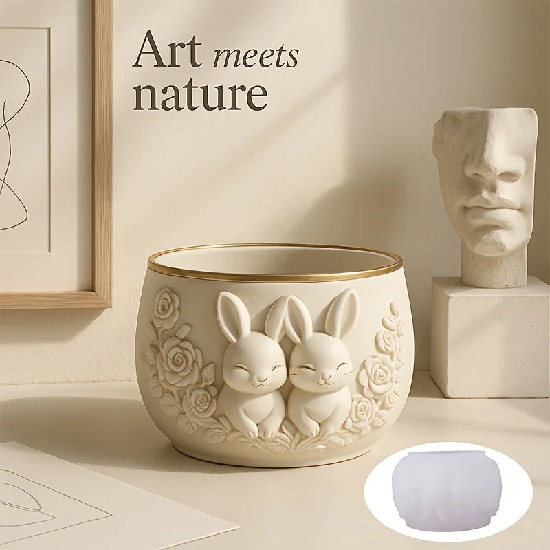 Bunny couple planter pot with floral relief, shown next to artwork and bust sculpture