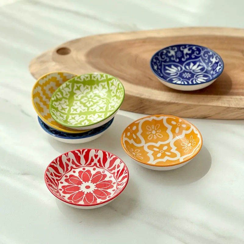Stack of small mandala ceramic plates and a few displayed on a tray in natural light