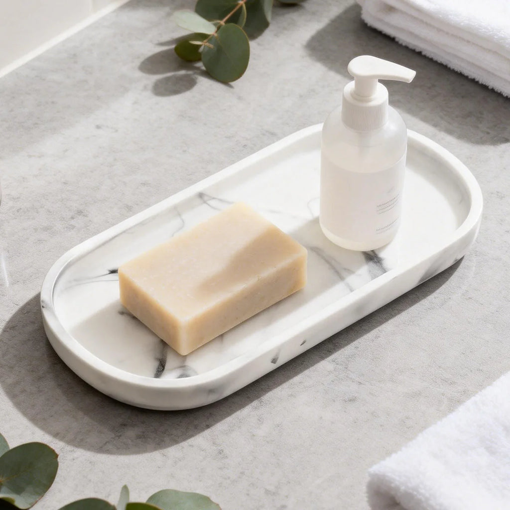 White marble-look matte silicone oval vanity tray with soap and a dispenser on a bathroom counter