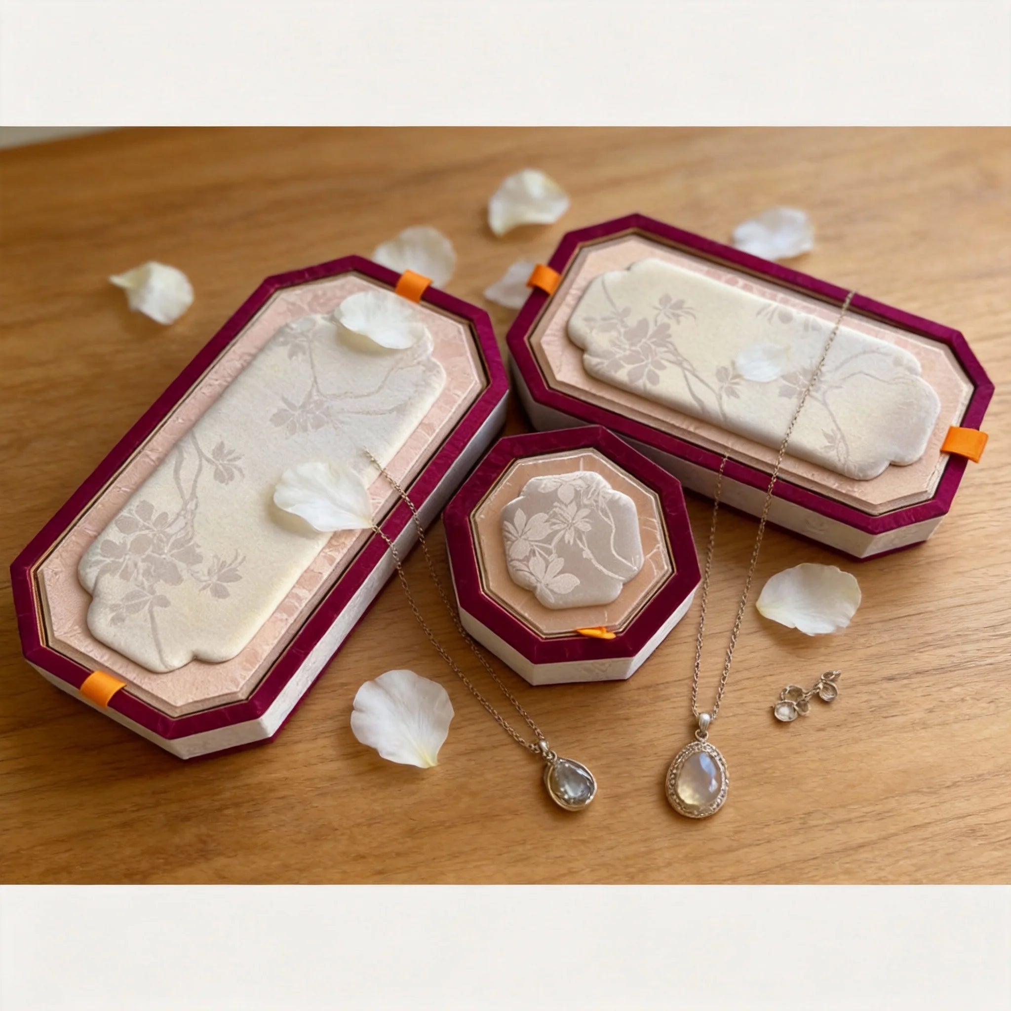 Floral padded jewelry trays displayed with necklaces and stud earrings on a wood tabletop