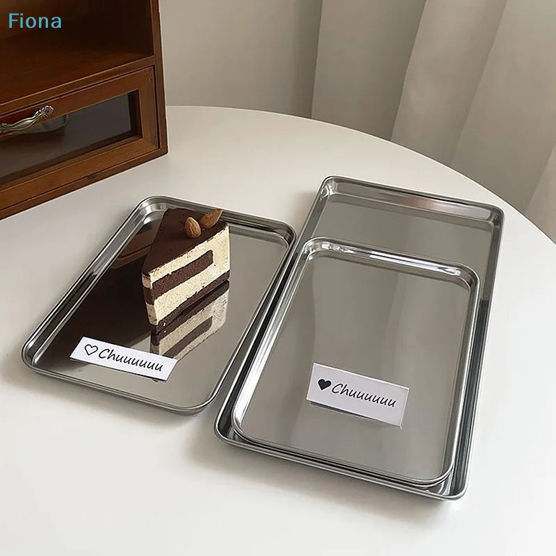 Three rectangular stainless steel trays on a white surface, one holding a slice of cake