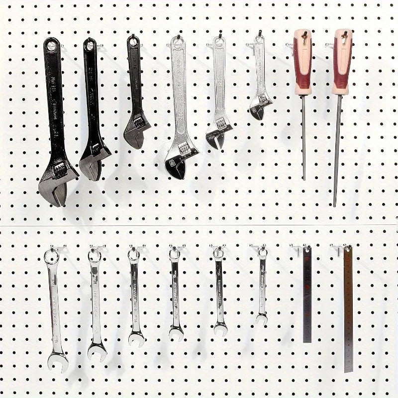 multiple wrenches and screwdrivers hanging on a white pegboard with metal hooks for tool storage