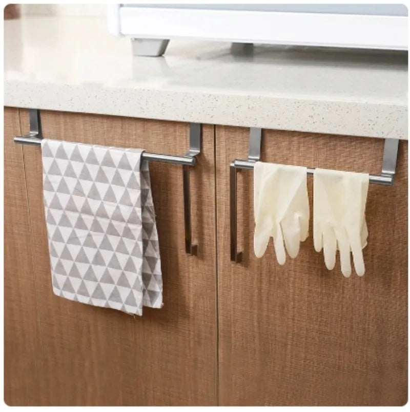 Stainless steel over-cabinet towel bars on brown cabinet doors, holding a towel and cleaning gloves in a kitchen