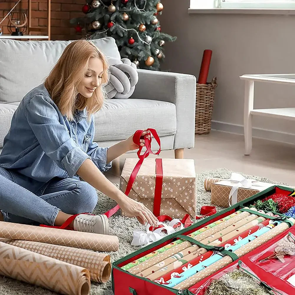 Woman sitting in a living room, organizing ribbons and gift wrap beside a green and red holiday wrapping paper storage bag filled with wrapping supplies