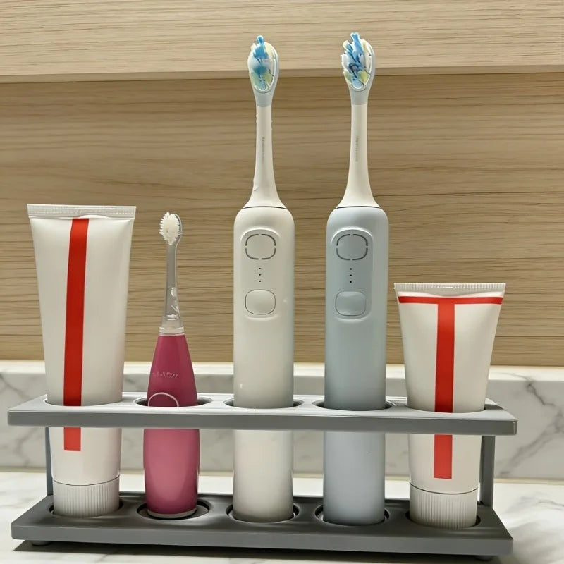 gray countertop toothbrush holder with electric toothbrushes and toothpaste in a light bathroom setting