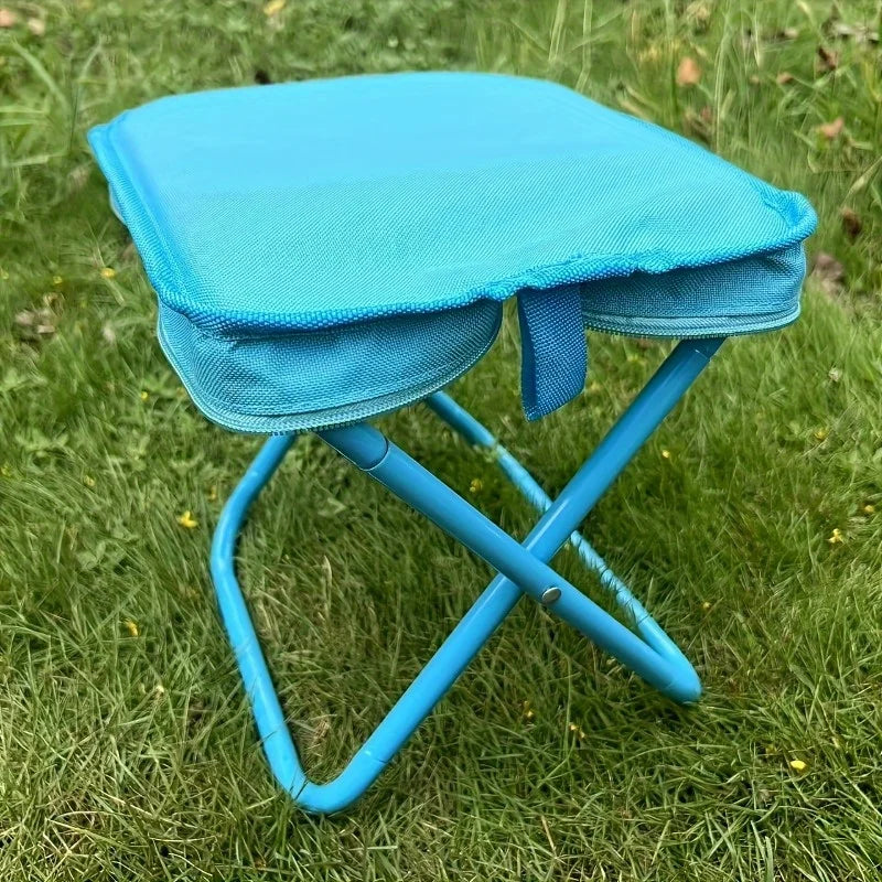 Bright blue folding outdoor stool with zippered seat, placed on grass