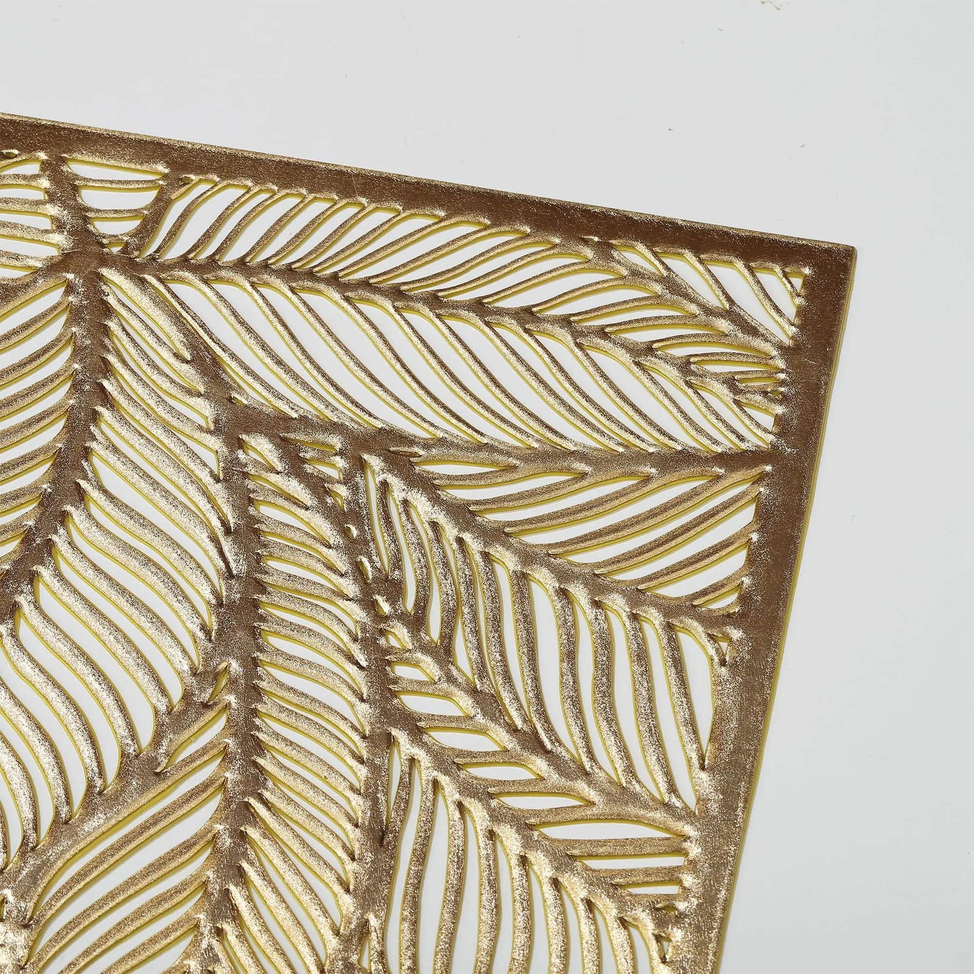 Close-up detail of hollow leaf cutout design in gold PVC placemat