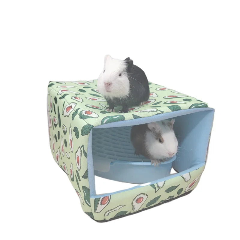 Guinea pigs next to a blue corner litter tray inside a cube-patterned shelter