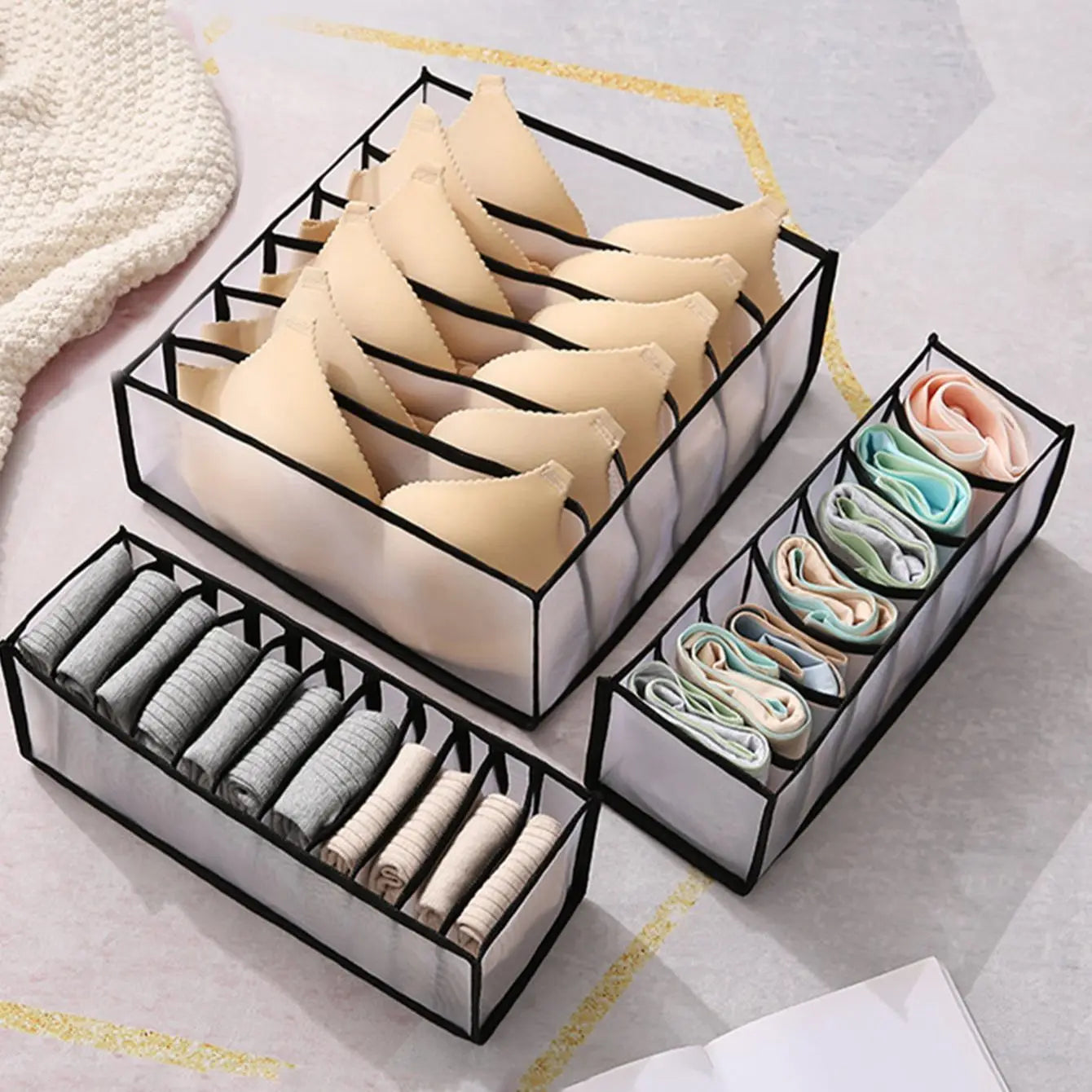 Hand placing a sock organizer box into a dresser drawer alongside other organizers