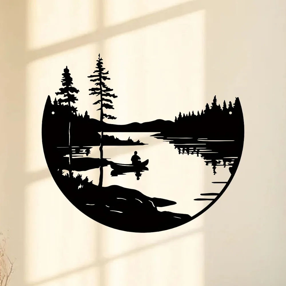 Round black metal wall art showing a kayaker on a lake with trees and mountains, mounted on an interior wall