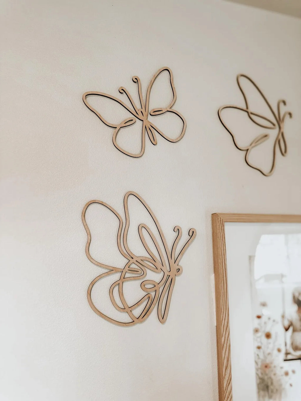 Close-up of wooden butterfly wall decor in various sizes clustered near framed artwork