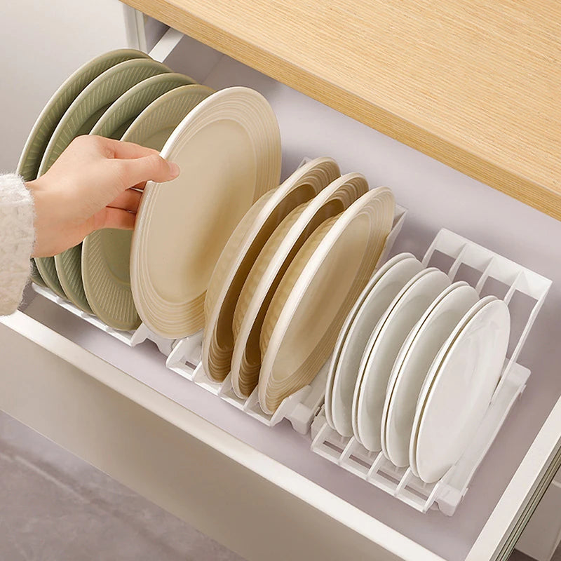 Hand placing a plate onto a white vertical organizer rack with plates sorted in a kitchen drawer.
