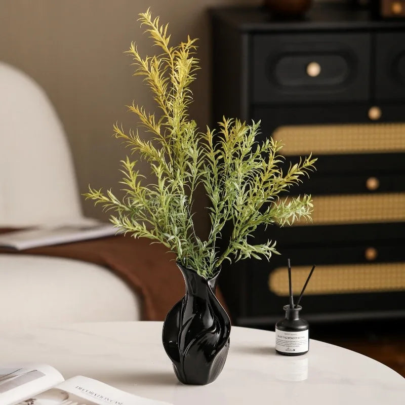 black ceramic vase with green foliage on a coffee table