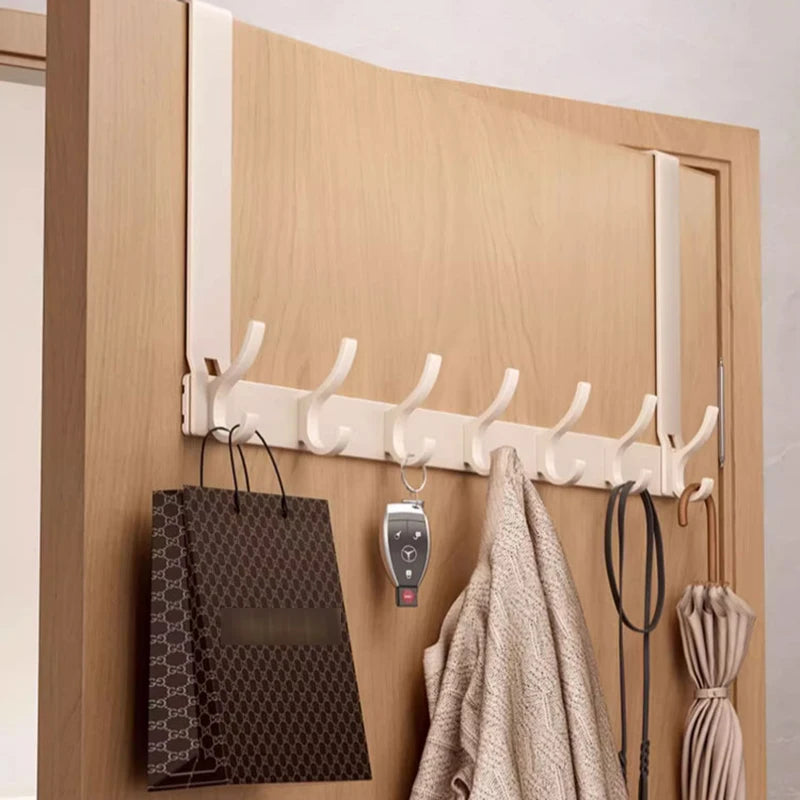 Cream aluminum over-the-door organizer rack holding bags, a sweater, a key, and an umbrella