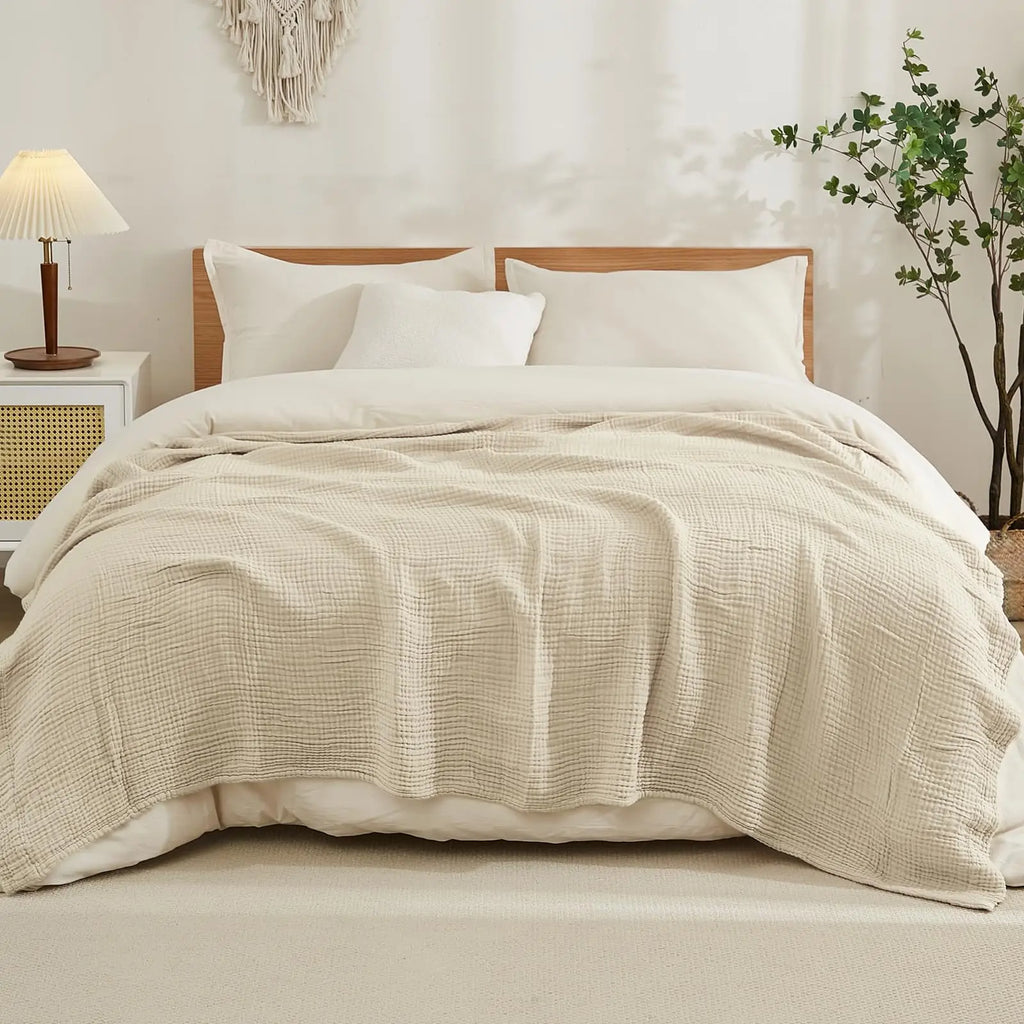 beige cotton muslin blanket on a made bed in a neutral bedroom