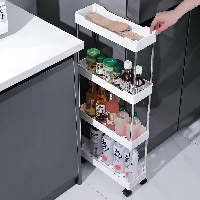Slim white rolling storage cart organized with bottles and kitchen supplies in a narrow gap beside a counter