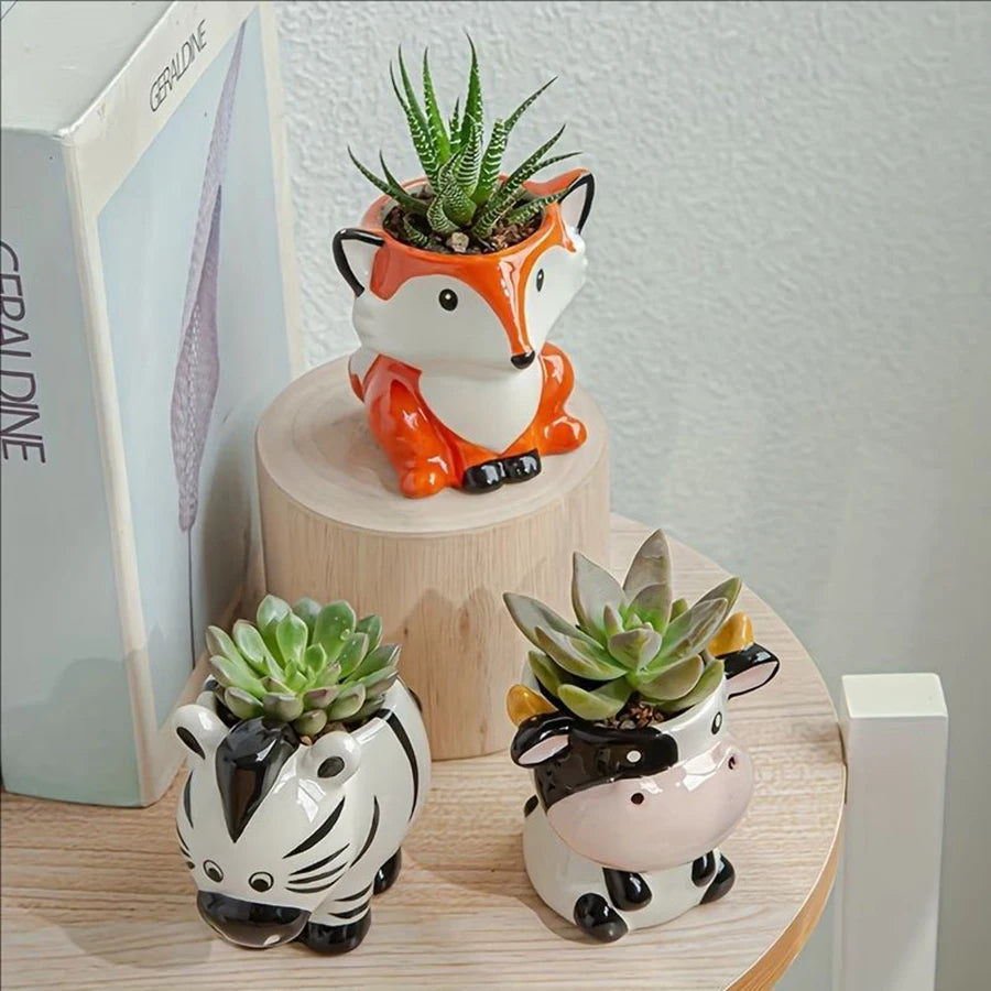 Close-up of fox, zebra, and cow animal ceramic planters with succulents on a round shelf