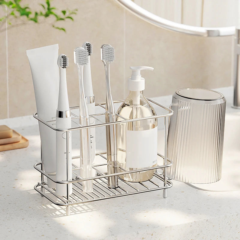 Stainless steel bathroom toothbrush organizer holding electric toothbrushes, toothpaste, and a clear bottle on a sink