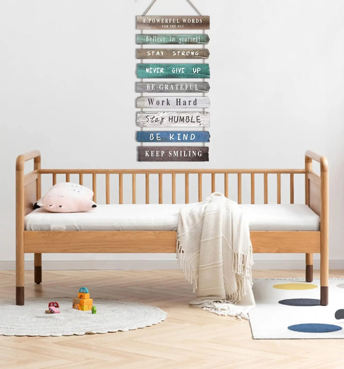 Motivational wooden wall sign with positive phrases above a wooden bed in a minimalist kids room