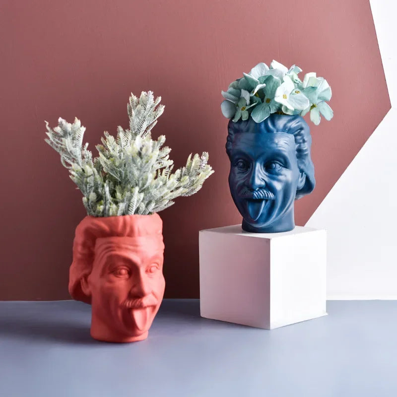 Red and blue resin head vases on geometric blocks with green and blue flowers