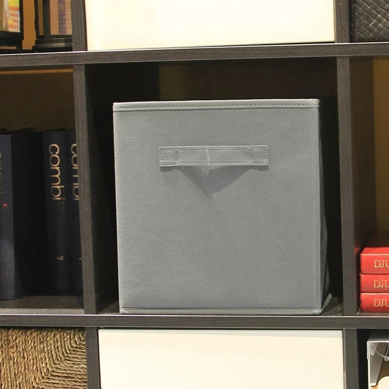 Grey fabric cube storage bin in a bookshelf cubby for home organization