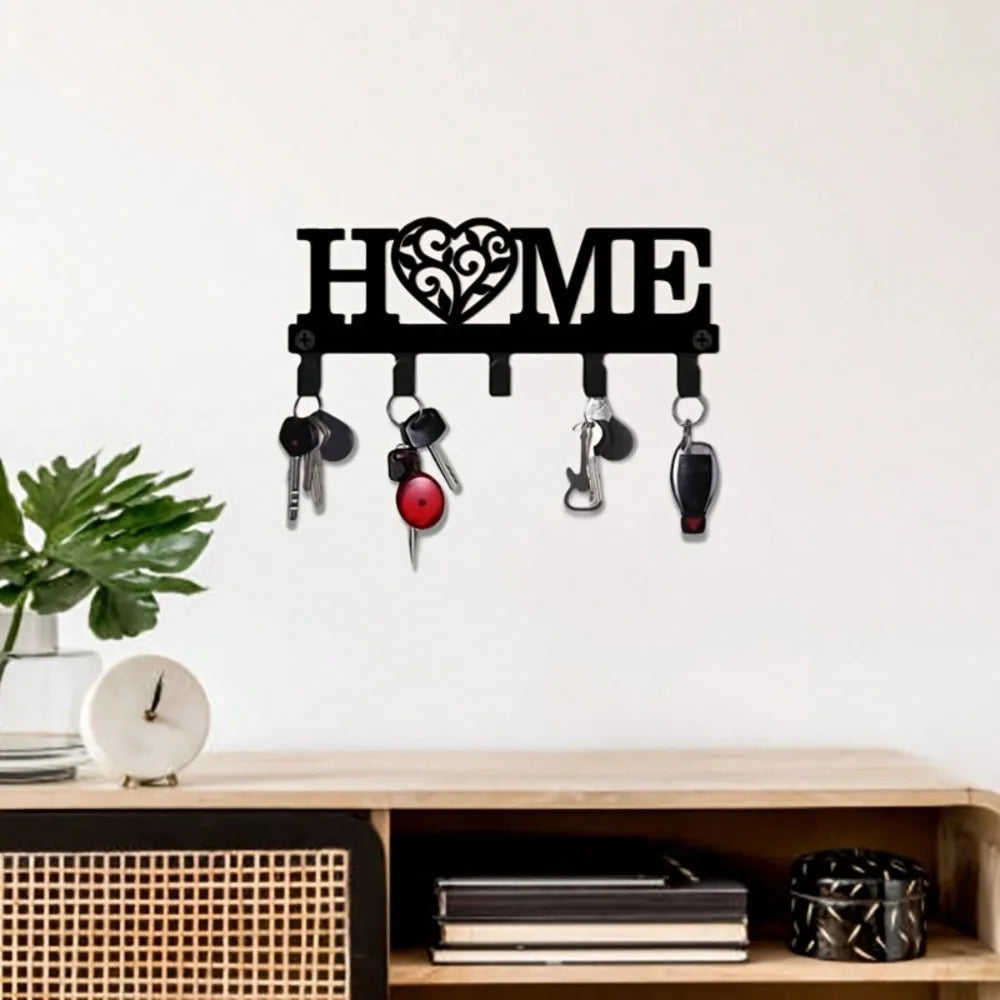 Black metal 'HOME' key rack with keys, wall-mounted above a console in an entryway with decor